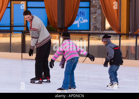 Two children chasing their father while skating at Northstar ski resort near Truckee, California Stock Photo