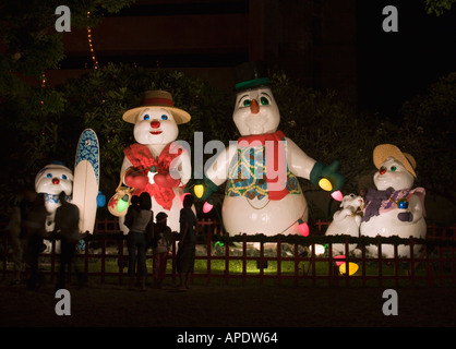 Four big toy model Christmas characters of a snowman family illuminated at night in central Honolulu Oahu Island Hawaii Stock Photo