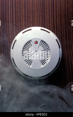 Smoke alarm on ceiling with smoke Stock Photo