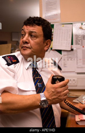 Security guard on duty in CCTV control room talking on radio, Lewisham Shopping Centre, London, UK. Stock Photo