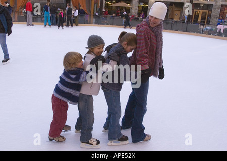 A mother and three children ice skating in a line at Northstar ski resort near Lake Tahoe in California Stock Photo