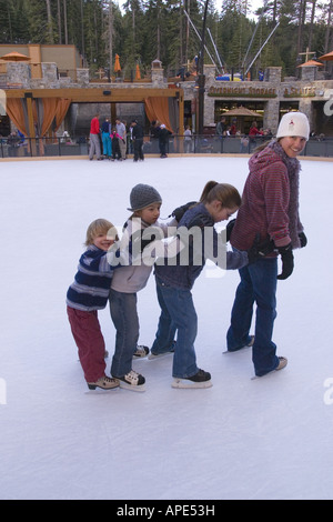 A mother and three children ice skating in a line at Northstar ski resort near Lake Tahoe in California Stock Photo