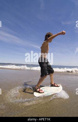 A young boy skim boarding on the beach on the Pacific Ocean in Santa Cruz, California Stock Photo