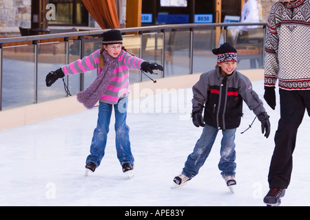 Two children chasing their father while skating at Northstar ski resort near Truckee, California Stock Photo