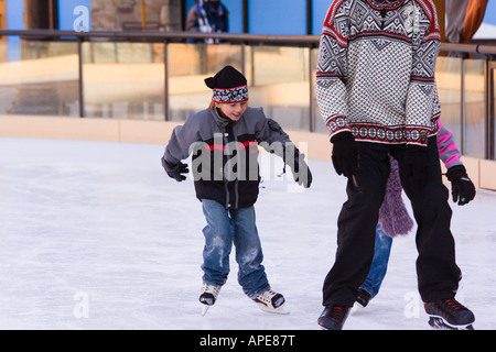 Two children chasing their father while skating at Northstar ski resort near Truckee, California Stock Photo