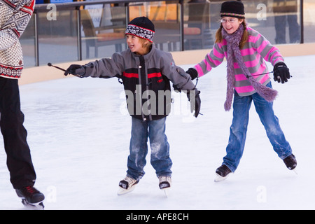 Two children chasing their father while skating at Northstar ski resort near Truckee, California Stock Photo