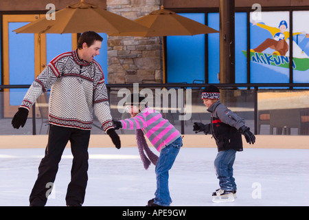 Two children chasing their father while skating at Northstar ski resort near Truckee, California Stock Photo