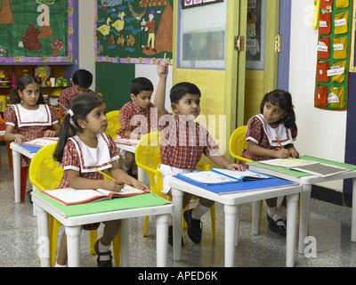 South Asian Indian boy raising hand for replaying answer in nursery school MR Stock Photo