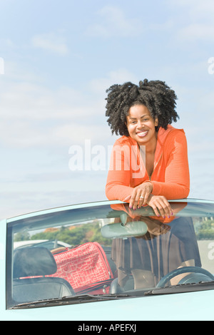 African woman standing in convertible car Stock Photo