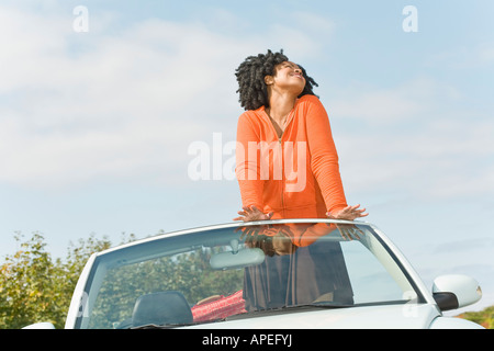 African woman standing in convertible car Stock Photo