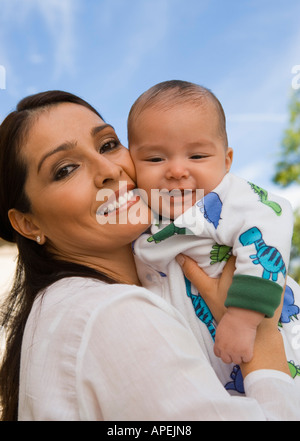 Mother embracing baby (6-12 months), outdoors, (portrait)