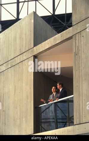 Asian American and Caucasian executives speaking in corporate office tower atrium Stock Photo