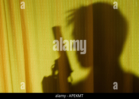 Silhouette of man with gun behind curtain. Stock Photo