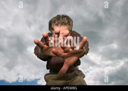 Middle age man, with his arms outstretched, posing in front of a cloudy sky. Stock Photo