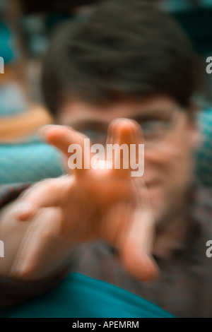 Young man, wearing glasses, gesturing with his hand.  MODEL RELEASED. Stock Photo