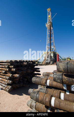 Oil rig drill pipes stacked with oil industry workers in the background ...
