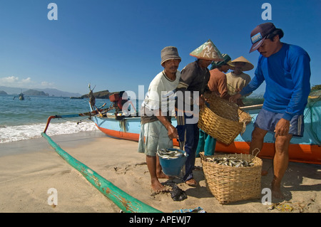 Indonesian fishermen near their boat and fishing nets, on a beach in the eastern part of Java island, Indonesia. Stock Photo