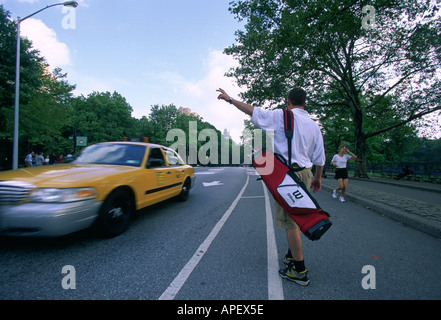 Golfer flagging a yellow taxi cab, golf bag on shoulder Stock Photo