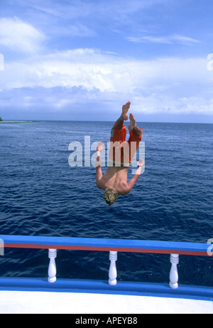 Man jumping backwards off boat into water Stock Photo