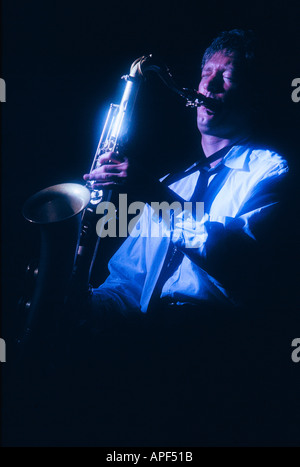 Young man playing tenor saxophone.  Blue light Night club atmosphere Stock Photo