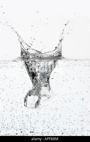 Two ice cubes dropping into fizzy water Stock Photo