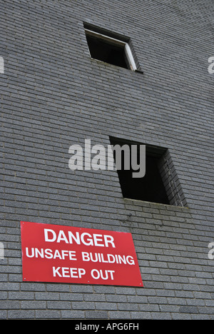 A derelict building with a warning sign 'Danger unsafe building keep out' Stock Photo