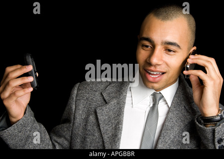 young mixed race businessman chatting on two mobile phones Stock Photo