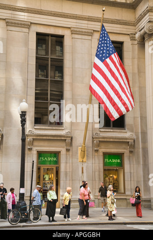 ILLINOIS Chicago People waiting at bus stop on LaSalle Street, American flag, financial district, sidewalk Stock Photo