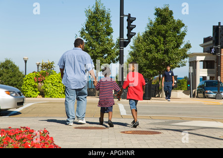 WISCONSIN Racine African American father crossing street with two boys in pedestrian crosswalk downtown area Stock Photo