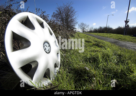 silver wheel hub cap discarded at the side of the road on a sunny day Stock Photo