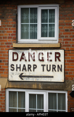 A house protected on a sharp bend by a large sign reading 'danger sharp turn'. Picture by Jim Holden Stock Photo