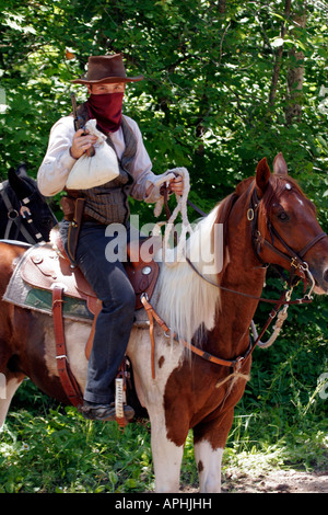 A cowboy bandit holding the money bag that was stolen from a steam train Robbery Reenactment Stock Photo