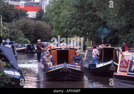 Two smiling mature men sitting on the foredeck of a narrowboat with two smiling women at the helm, Banbury Oxfordshire, England Stock Photo