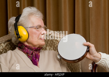 Elderly lady wearing ear ^defenders and looking ^annoyed Stock Photo