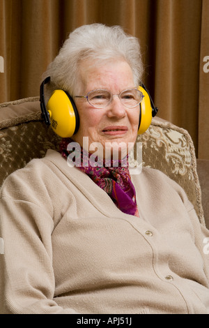 Elderly lady wearing ear ^defenders and looking smug Stock Photo