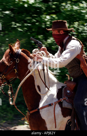 A cowboy bandit with a loaded single action shooting western gun on horseback riding to rob a train Stock Photo