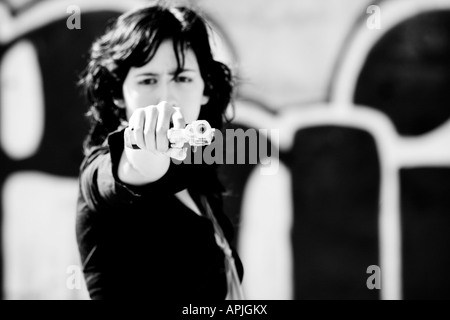 Young woman aiming at the camera Focus in the gun barrel Stock Photo