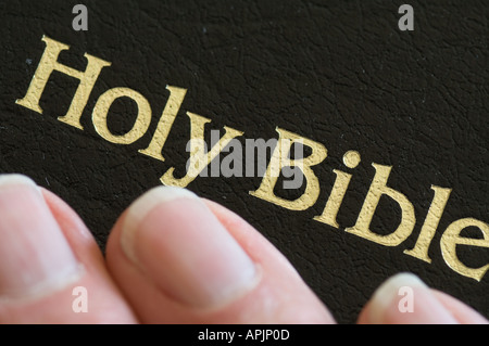 closeup of hand touching Holy Bible during prayer Stock Photo
