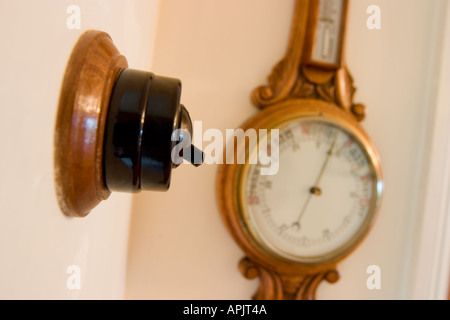 OLD FASHIONED BAKELITE LIGHT SWITCH WITH BAROMETER IN BACKGROUND Stock Photo