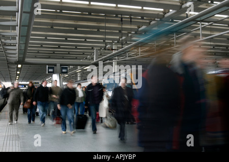 Passengers pour off an East Midlands Trains Class 222 meridian at St Pancras but it is yet to be repainted It is still in Midland Mainline livery. Movement blur prevents individual identity and maintains the idea of people wanting to get to their destination quickly. St. Pancras Station, London, UK. Stock Photo