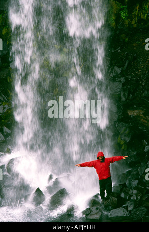 Carl Galvin in a red Mountain Equipment gore tex jacket under Svartifoss Waterfall in Iceland Stock Photo