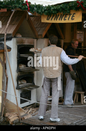 A Baker placing a loaf in the oven. Stock Photo