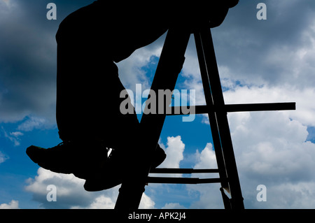 silhouette of man sitting on step ladder looking at  clouds Stock Photo