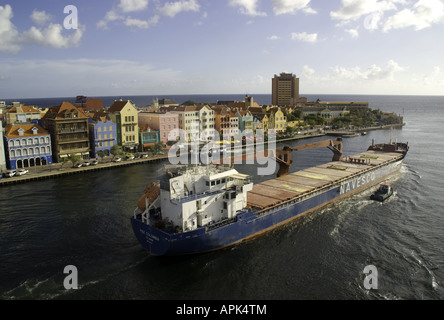 Willemstad's Punda waterfront pastel Dutch architecture with Navesco freighter Paz Colombia leaving port Stock Photo