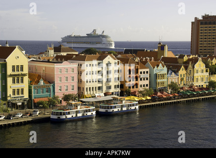 Willemstad's Punda waterfront pastel Dutch architecture with Royal Caribbean cruise ship Adventure of the Seas leaving port Stock Photo
