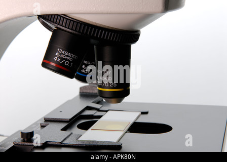 Close up of a microscope in a research lab showing the objective lenses and a slide Stock Photo
