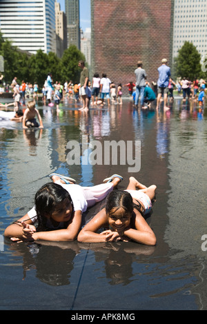 ILLINOIS Chicago Two girls lying down in shallow water children play around Crown Fountain in Millennium Park Stock Photo