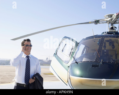 Businessman using cell phone near helicopter Stock Photo