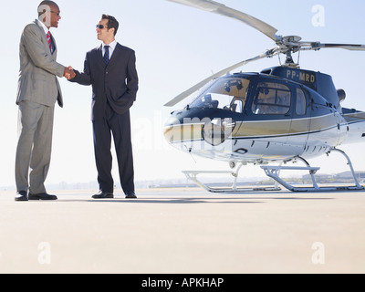 Two businessmen shaking hands near helicopter (low angle view) Stock Photo
