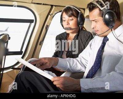 Two businesspeople wearing headsets and talking in helicopter Stock Photo